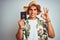 Young handsome man holding United States passport over white isolated background doing ok sign with fingers, excellent symbol