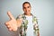 Young handsome man on holidays wearing Hawaiian shirt over white background smiling friendly offering handshake as greeting and