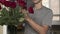 Young handsome man with a little stubble in a gray T-shirt straightens fixing and sniffs a beautiful bouquet of red