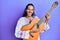 Young handsome man with long hair playing classical guitar smiling and laughing hard out loud because funny crazy joke