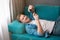 Young handsome man lying on the sofa with smartphone in his hand looking happy, carefree life