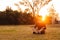 Young handsome man in a meditative position sits on a lawn on a background of forest and sunset. Concept of freedom relaxation.