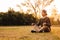 Young handsome man in a meditative position sits on a lawn on a background of forest and sunset. Concept of freedom relaxation.