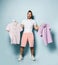 Young handsome man in pink shorts and white t-shirt standing decide, holding two polo shirts feeling crazy unable to chose