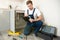 Young handsome man plumber looks concentrated while checking instruction during pipe fixing work in the kitchen