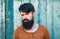 Young handsome man, portrait face of serious bearded hipster on wooden background.