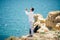 Young handsome Man praying in beautiful inspiring ocean coast enjoy inspirational landscape on rocky top