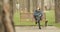 Young handsome man puts on his headphones and starts listening to music moving his head to a bit while sitting on bench in park.