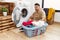 Young handsome man putting dirty laundry into washing machine disgusted expression, displeased and fearful doing disgust face