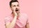 Young handsome man shouting and screaming loud to side with hand on mouth and copy space for text on pink background