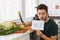 A young handsome man sits in the kitchen with an angry face and asks for help.