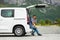 Young handsome man sitting in the trunk of his hired car and talking on the mobile phone on mountains background. Car hire. Car