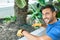 Young handsome man smiling happy caring plants using garden shovel at terrace