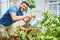 Young handsome man smiling happy caring plants using watering can at terrace