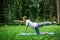 Young handsome man in sportswear does stretching in the park on the green grass. Prepare a warm-up for yoga or fitness classes