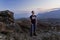 A young handsome man stands high in the mountains and looks at sunset.