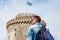 Young handsome man in sunglasses, tourist, with backpack is watching on a White Tower in the Thessaloniki, Greece