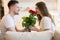 Young handsome man surprising his beautiful wife with roses on saint valentine`s day, happy romantic unniversary