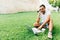 Young handsome man talking on the phone while working on laptop on the grass in park