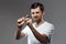 Young handsome man trying to break shaver over grey background.