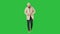 Young handsome man walks and buttons up cloak on a green screen, chroma key.