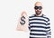 Young handsome man wearing burglar mask holding money bag with dollar symbol thinking attitude and sober expression looking self