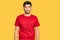 Young handsome man wearing casual red tshirt looking sleepy and tired, exhausted for fatigue and hangover, lazy eyes in the