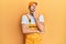 Young handsome man wearing handyman uniform over yellow background bored yawning tired covering mouth with hand