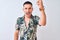 Young handsome man wearing Hawaiian summer shirt over  background angry and mad raising fist frustrated and furious while