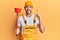 Young handsome man wearing plumber uniform holding toilet plunger smiling with an idea or question pointing finger with happy