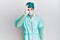 Young handsome man wearing surgeon uniform and medical mask doing ok gesture shocked with surprised face, eye looking through