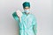 Young handsome man wearing surgeon uniform and medical mask looking unhappy and angry showing rejection and negative with thumbs