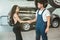 Young handsome mechanic and beautiful woman client shaking hands in gratitude for great service provided