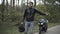 Young handsome Middle Eastern biker hitchhiking on roadside with broken motorcycle standing at the background. Portrait