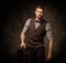 Young handsome old-fashioned man with briefcase posing on dark background.