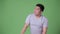 Young handsome overweight Asian man against green background