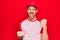 Young handsome player man wearing baseball sportswear over isolated red background celebrating surprised and amazed for success