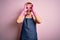 Young handsome redhead cleaner man doing housework wearing apron and gloves doing ok gesture like binoculars sticking tongue out,