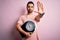 Young handsome slim sportsman with beard holding scale over isolated pink background with open hand doing stop sign with serious