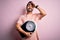 Young handsome slim sportsman with beard holding scale over isolated pink background stressed with hand on head, shocked with