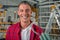 Young handsome smiling caucasian carpenter holds safety glasses in his hands in his workshop