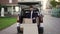 Young handsome smiling Caucasian delivery man with boxes on cart moving tovard to van with opened truck. Male post