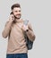 Young handsome smiling man talking on mobile phone. Student men using smartphone. Isolated closeup studio portrait, gray backgroun