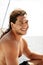 A young handsome sports guy with long hair on the deck of a tourist boat.