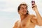 A young handsome sports guy with long hair does selfie on a smartphone on the deck of a tourist boat.