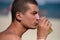 Young handsome sporty man drinking beer at the beach in summertime - relaxing, summer, thirsty concept. Resort relaxation. Sea in