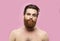 Young handsome strong man with beard shirtless standing over isolated pink background, looking at the camera.