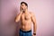 Young handsome strong man with beard shirtless standing over isolated pink background Yawning tired covering half face, eye and