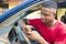 young handsome taxi driver seating down in his car operating his cellphone