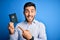 Young handsome tourist man holding australia australian passport id over blue background very happy pointing with hand and finger